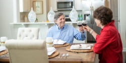 Photograph of a couple toasting wine at the dinner table