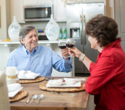 Photograph of a couple toasting wine at the dinner table